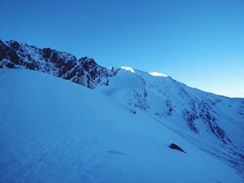 Scenic view of snowcapped mountains against clear blue sky