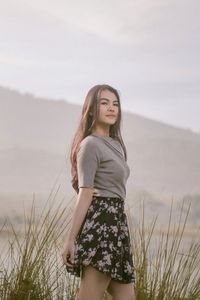 Young woman standing against the sky