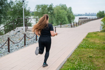 Full length rear view of woman on footpath