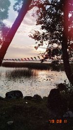 Scenic view of lake by silhouette trees against sky