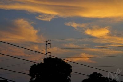 Low angle view of silhouette electricity pylon against sky during sunset