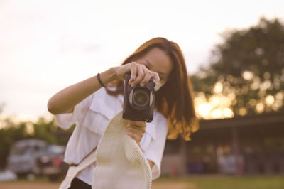 Young woman using camera ,bokeh of golden hour in background