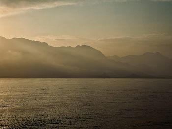Scenic view of sea and mountains against sky during sunset