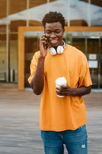 Midsection of man holding smart phone while standing outdoors