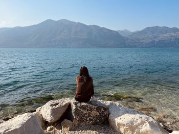 Girl sitting on a rock looking at the lake landscape