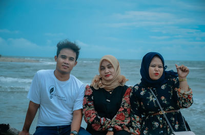 Young couple standing in sea against sky