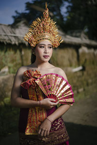 Young woman in traditional clothing looking away against house