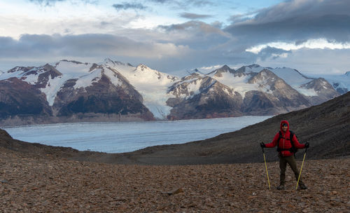Rear view of man standing on snowcapped mountains against sky