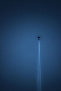 Low angle view of airplane flying against clear blue sky