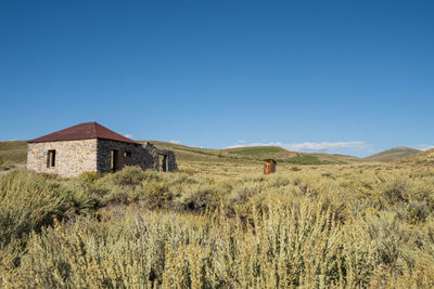 House on field against clear blue sky in ghost town