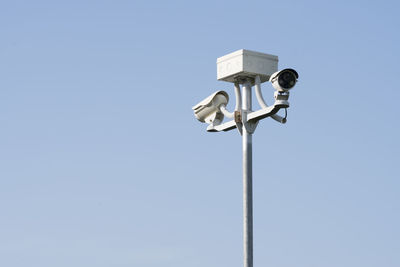 Low angle view of security cameras against sky