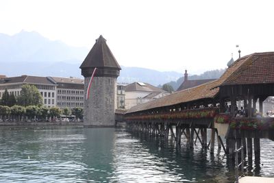 Bridge over river by buildings against clear sky