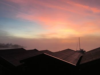 High angle view of silhouette houses against cloudy sky during sunset