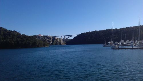 Boats in calm river against clear sky