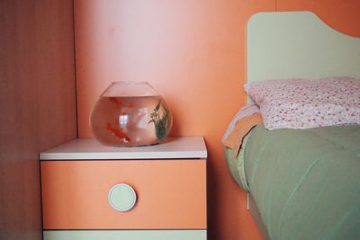 Close-up of vase and bed against wall at home