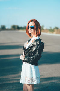 Woman wearing sunglasses standing on road against sky