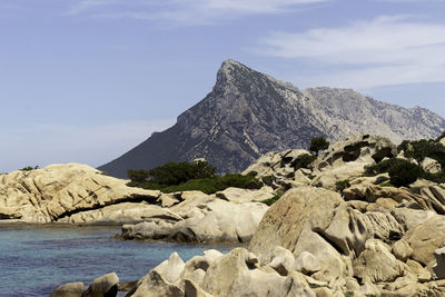 Beautiful sardinian sea shore landscape with granite rocks and isola cana in the background.