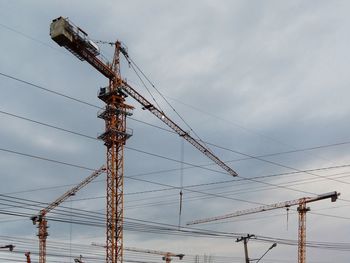 Low angle view of cranes against sky