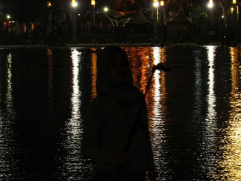 Reflection of woman in lake at night