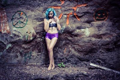 Full length of female model wearing corset while standing by carvings on rock