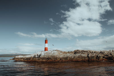 Lighthouse by sea against sky