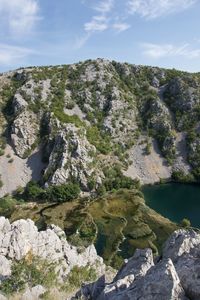 Scenic view of river, rocks and plants against sky