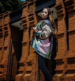 Portrait of woman standing against wall