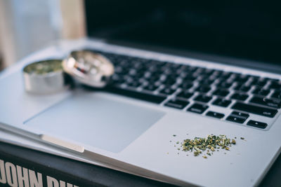 Close-up of marijuana and grinder on laptop