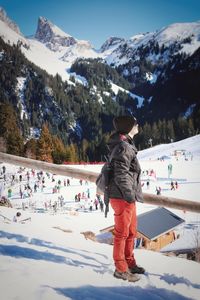 Side view of mid adult woman standing on snowcapped mountain