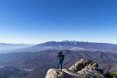 Man standing on mountain against clear blue sky