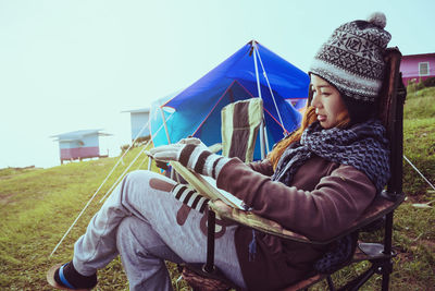 Side view of young woman sitting on field