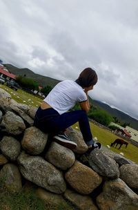 Rear view of woman on rock against sky