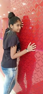 Portrait of girl standing against red wall