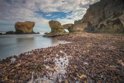 Rocks on shore by sea against sky