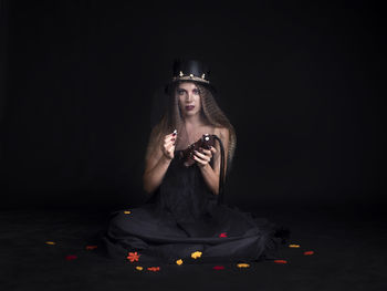 Portrait of woman standing against black background