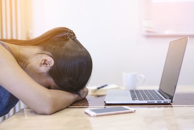 Midsection of woman using mobile phone while sitting on table