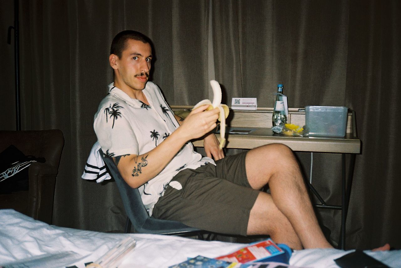 YOUNG MAN SITTING ON BED WITH HOME