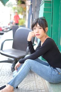 Young woman looking away while sitting outdoors