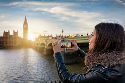 Woman photographing big ben through mobile phone in city