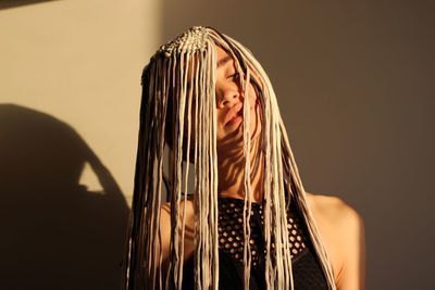 Close-up of woman wearing headwear by wall