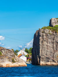 Rock formations in sea against clear blue sky