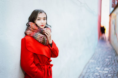 Portrait of young woman wearing warm clothing standing in alley