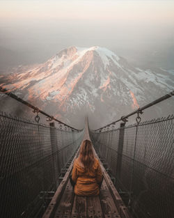 Rear view of woman on snowcapped mountain against sky