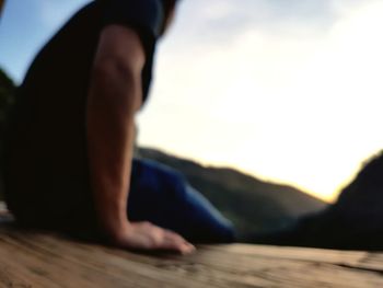 Low section of man sitting against sky