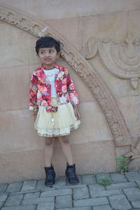 Portrait of girl standing against brick wall