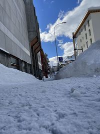 Snow covered street by buildings against sky