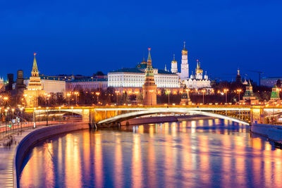 Illuminated bridge over river against blue sky