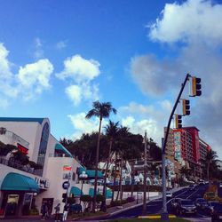 Cars on city street against cloudy sky