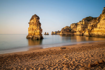 View of rock on beach against clear sky