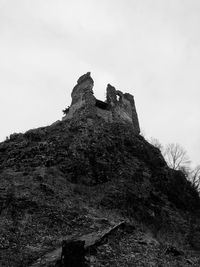 Low angle view of cross on rock against sky